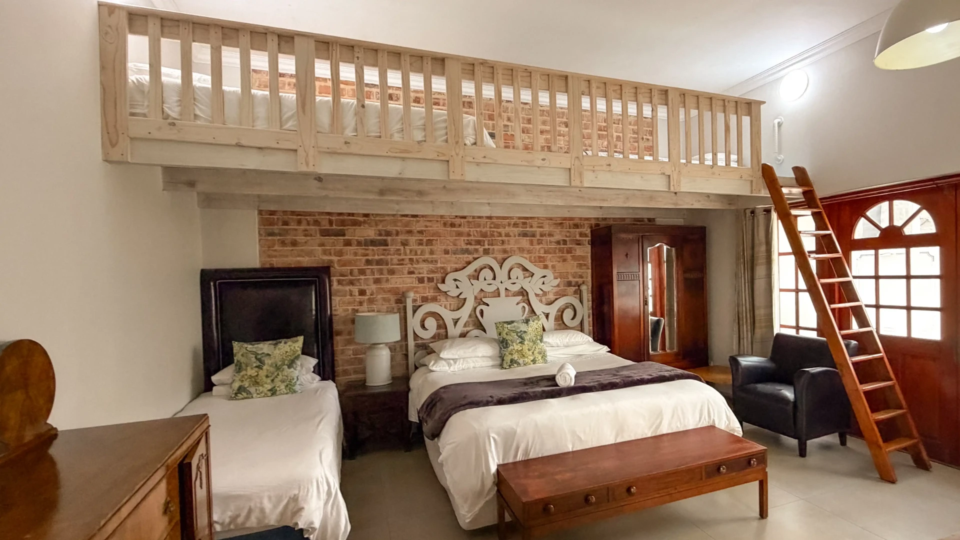 Loft bedroom with twin and double beds at Blouberg Manor